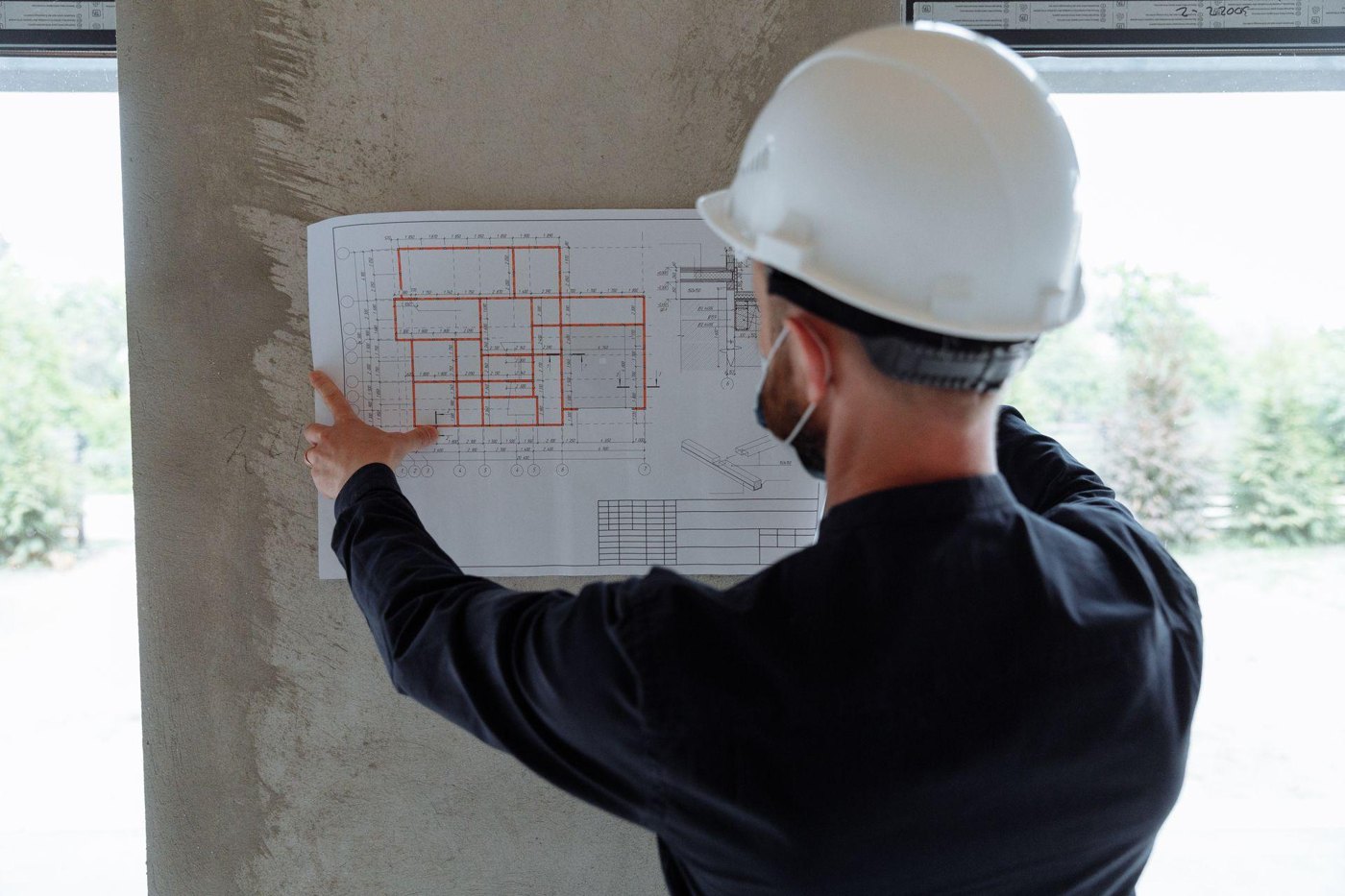 Construction professional in a hard hat checking a dimensioned plan on site